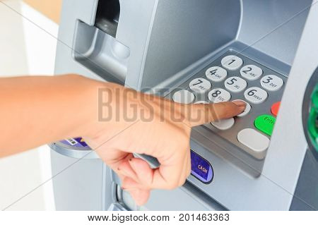 Close up of hand entering pin at an ATM. Finger about to press a pin code on a pad. Security code on an Automated Teller