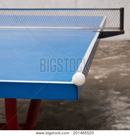 white pingpong ball hits the corner of a blue pingpong table