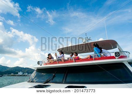 Langkawi, Malaysia - 3rd May 2017: Rich young people crusing on a yacht on sunny day with blue sky and whispy clouds. Shot in Langkawi on a sunset cruise