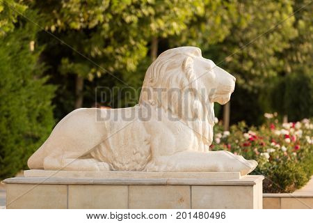Sculpture of a lion against a background of greenery and flowers