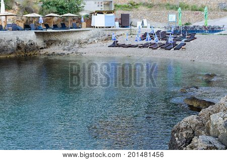 ULCINJ, MONTENEGRO - JULY 30, 2017: Small rock beach Liman on the Adriatic Sea in Ulcinj, Montenegro. Early morning time with empty beach beds, closed umbrellas and without people.