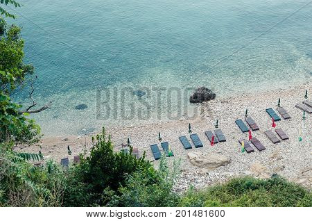 ULCINJ, MONTENEGRO - JULY 30, 2017: Small rock beach Liman on the Adriatic Sea in Ulcinj, Montenegro. Early morning time with empty beach beds, closed umbrellas and without people.