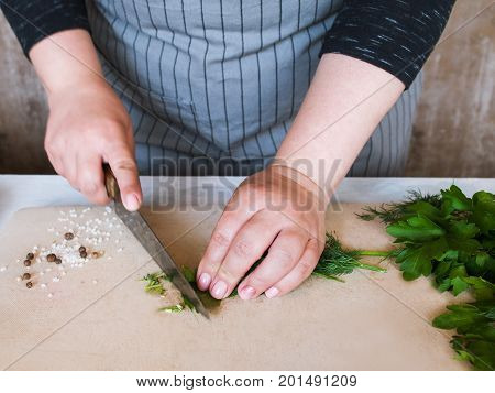 Cook chopping potherbs on wooden cutting board. Cooking process, healthy organic food and decoration, close up picture