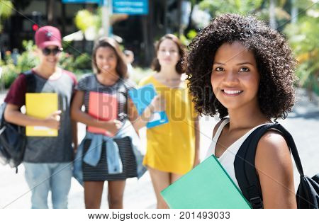Beautiful african american female student with group of international students outdoor in the city in the summer
