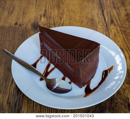 Piece Of Chocolate Cake With Spoon On White Plate
