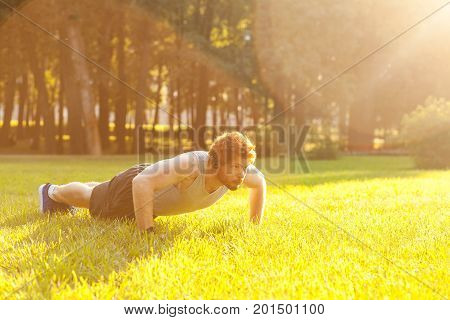 Push ups. Sunny. Summer. Redhead and bearded fitness model doing push ups. Outdoor
