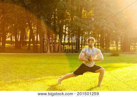 Happiness redhead sportsman doing gymnastic exercise in park.Looking at camera and smile.