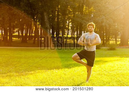 Happines bearded athlete doing yoga. Stay in one legs smiling and relax. Outdoor