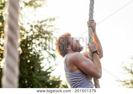 Climed up. Stronger young adult athlete climed up and looking up. Outdoor