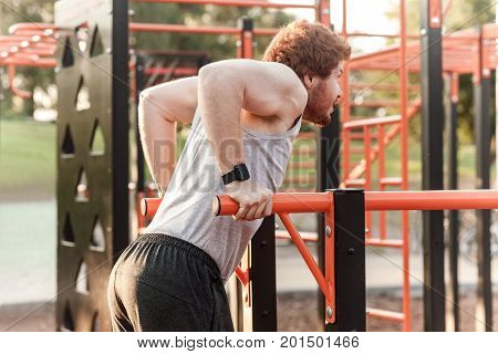 Young adult bearded redhead man doing pull ups. Outdoor