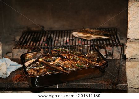 Fish grill / There are fish on the grill and grilled. An raw freshwater fish on the grill. Cooked in traditional style. Cooking of salted fish on a grill stove.