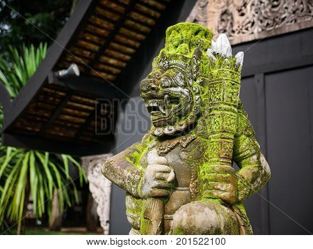 Balinese Carved Stone Statue of Rakasa covered with green moss. at Hindu Temple.