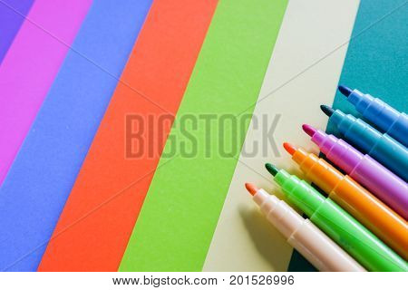 Colorful magic pens on colorful papers background.