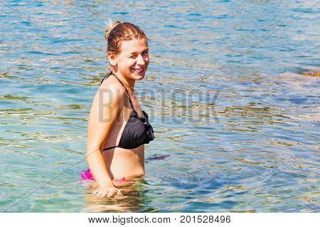 Picture of a happy young woman wearing swimsuit posing at the adriatic seashore Trogir Croatia