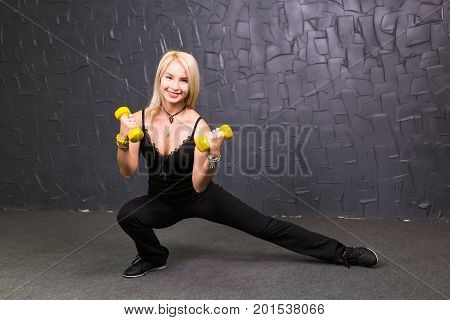 Attractive young fitness woman holding dumbell. Studio shot.