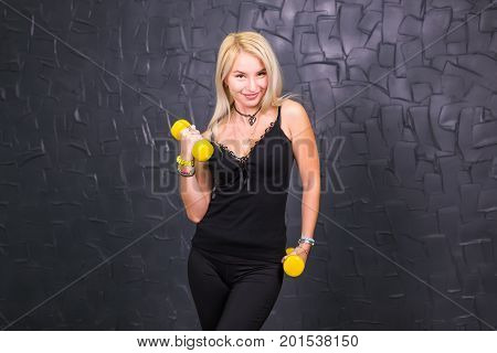 Attractive young fitness woman holding dumbell. Studio shot.