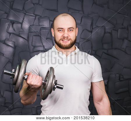 Good looking young man lifting dumbbells and working on his biceps