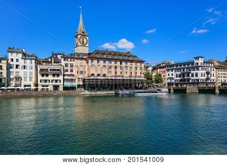 Zurich, Switzerland - 18 June, 2017: city's old town buildings along the Limmat river, clock tower of the St. Peter Church, Hotel Storchen. Zurich is the largest city in Switzerland and the capital of the Swiss canton of Zurich.