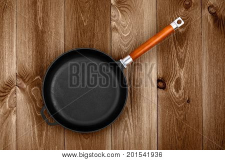 Empty cast iron skillet on a wooden table closeup top view
