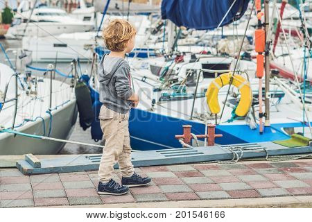 Cute Blond Boy Looking At Yachts And Sailboats