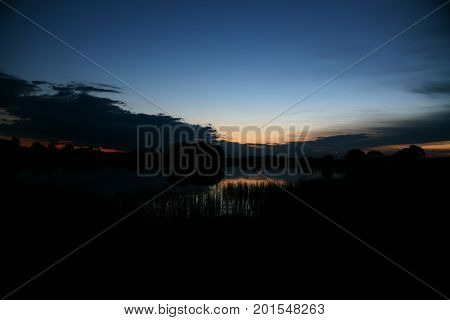 A calm pond surface with wood in nice sunrise with dawn and fog.