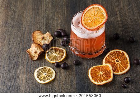 Cocktail on rustic wood background. Cold citrus alcohol beverage with tequila, blood orange juice and ginger beer, served with ice, citrons and chocolate snacks, copy space