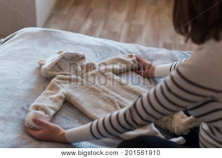 Pregnant woman dreaming and holding baby's clothes.