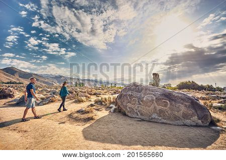 Couple Of Tourist Near Ancient Stone Painting