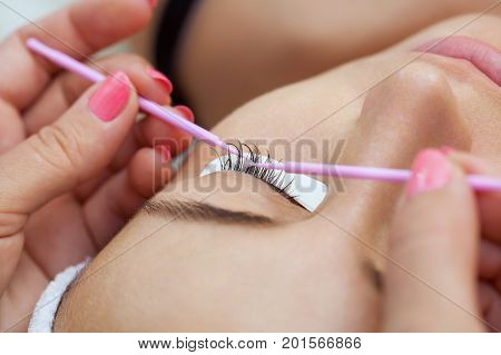 Eyelash removal procedure close up. Beautiful Woman with long lashes in a beauty salon. Eyelash extension.
