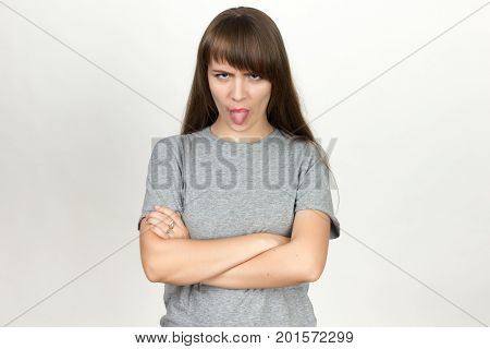 Woman shows tongue standing over gray background.