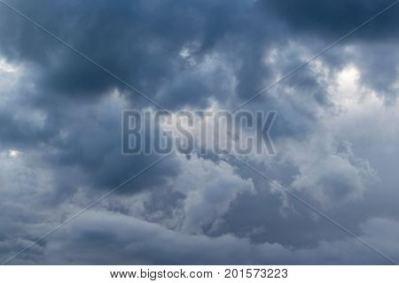 In the sky the storm clouds and the clouds. Bad weather. Strong wind and feeling the rain. The clouds are dark blue. The clouds are lit by sunlight.