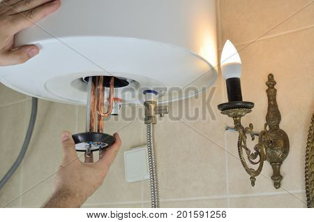 Man's hand installing a new water heater in a boiler