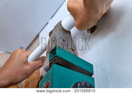 Plastic pipe welding machine plumber with welding machine connect plastic pipes installation of a water pipe on the wall hands working close-up.