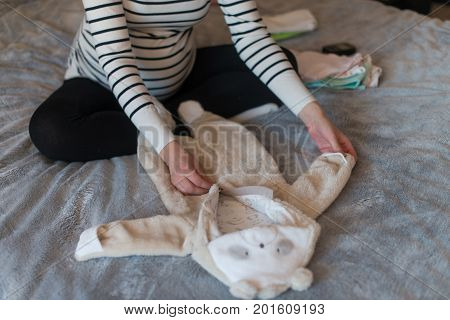 Pregnant woman dreaming and holding baby's clothes.