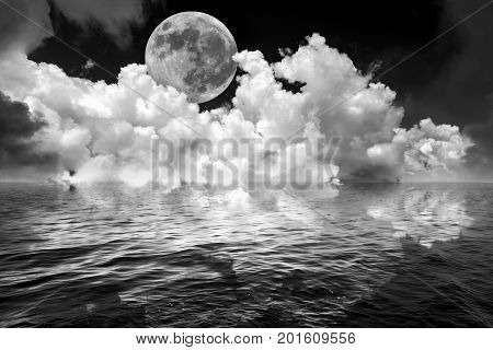 Full moon and clouds in dark fantasy night sky reflected in wavy ocean water