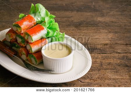 Fresh spring rolls with fresh vegetable and crab stick served with spicy salad cream dipping sauce. Rolls salad or fresh spring roll on white plate healthy delicious food for appetizer or meal. Fresh spring rolls in fusion food style.