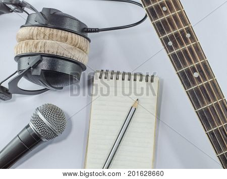 neck guitar notebook in top view with music concept whitebackground headphones