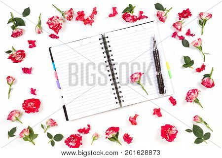 Open paper notebook and rose flowers on white background. Flat lay, top view