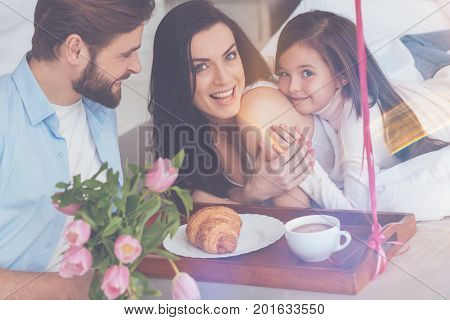 Closest people. Admirable caring inventive dad and daughter surprising their mom by bringing her breakfast in bed and a present while she just waking up