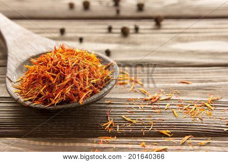 Spice saffron in wooden spoon and pepper on the table. Close-up.