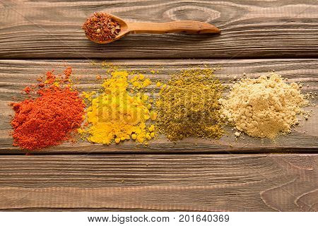 Spice powder and spoon with spices on wooden background. Close-up. Top view.