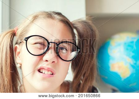 Neglecting the school. Nerdy funny girl with ponytails in eyeglasses. Indoors vibrant closeup horizontal image.
