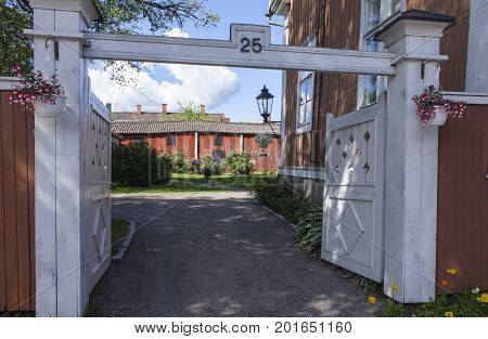 KOKKOLA, FINLAND ON JULY 07. View of an entry to a backyard on July 07, 2017 in Kokkola, Finland. Gate, flowers and a yard this side a wooden outhouse. Editorial use.