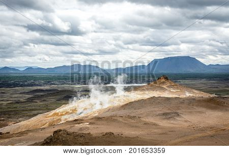 Mudpot in the Namafjall geothermal area, Iceland - area around boiling mud is multicolored and cracked.