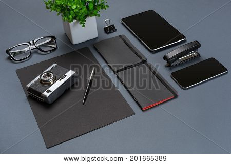 A set of black office accessories, glasses, old camera and tablet on gray background. Flat lay. Still life. Mock-up