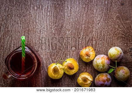 Glass with fresh Plum Juice on vintage wooden background. Top view. Copy space. Still life. Flat lay