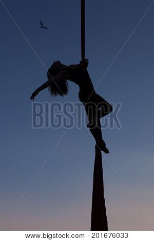 Woman is showing gymnastics in the air on a hammock.