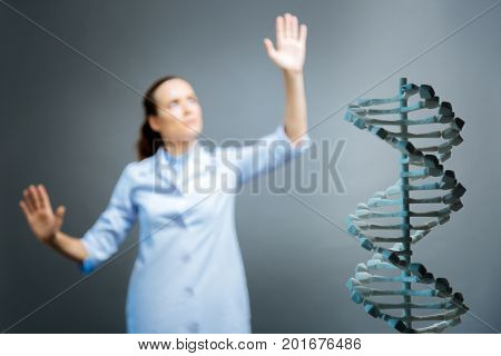 Advanced studying. Scaled up shot of a three dimensional dna model standing in front of a shot with a female medical worker leaning on an invisible touchscreen in the background.