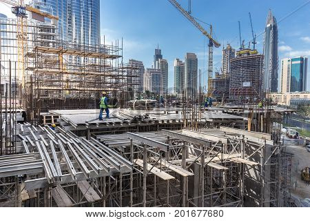 Laborers working on modern constraction site works in Dubai. Fast urban development consept.