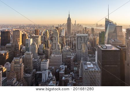 New York City. Manhattan downtown skyline with illuminated Empire State Building and skyscrapers at sunset.